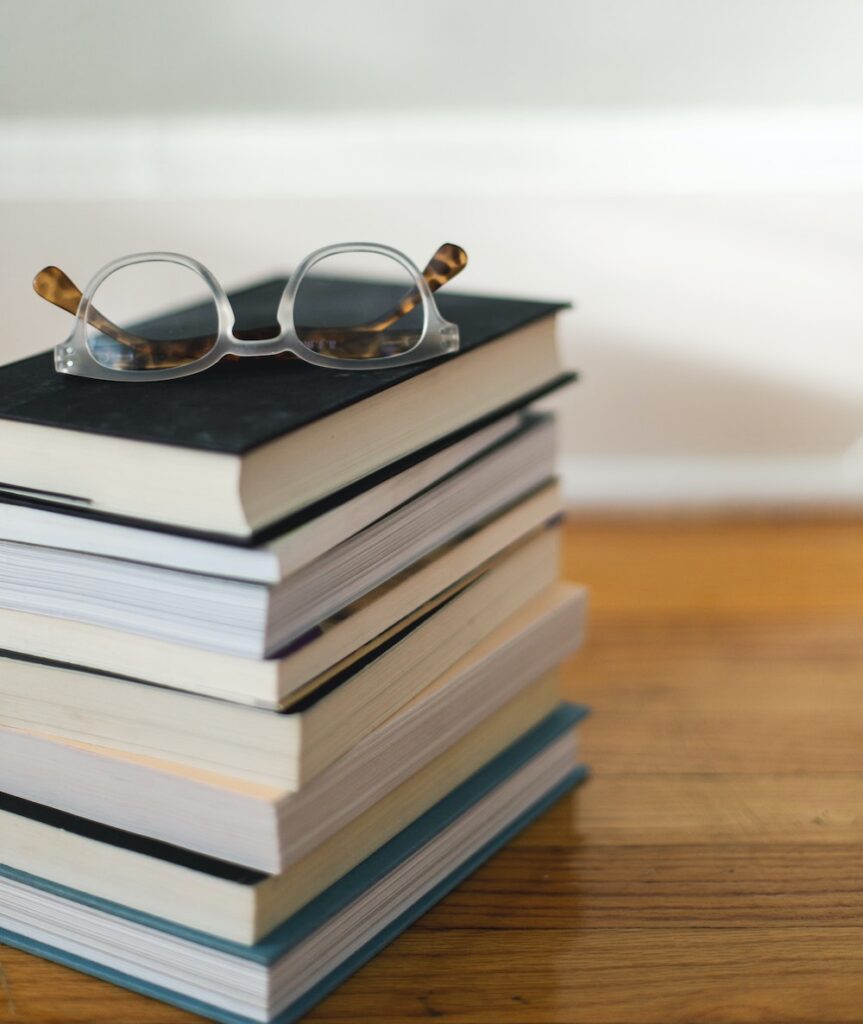 Stack of resources and books with a pair of glasses sitting on top.